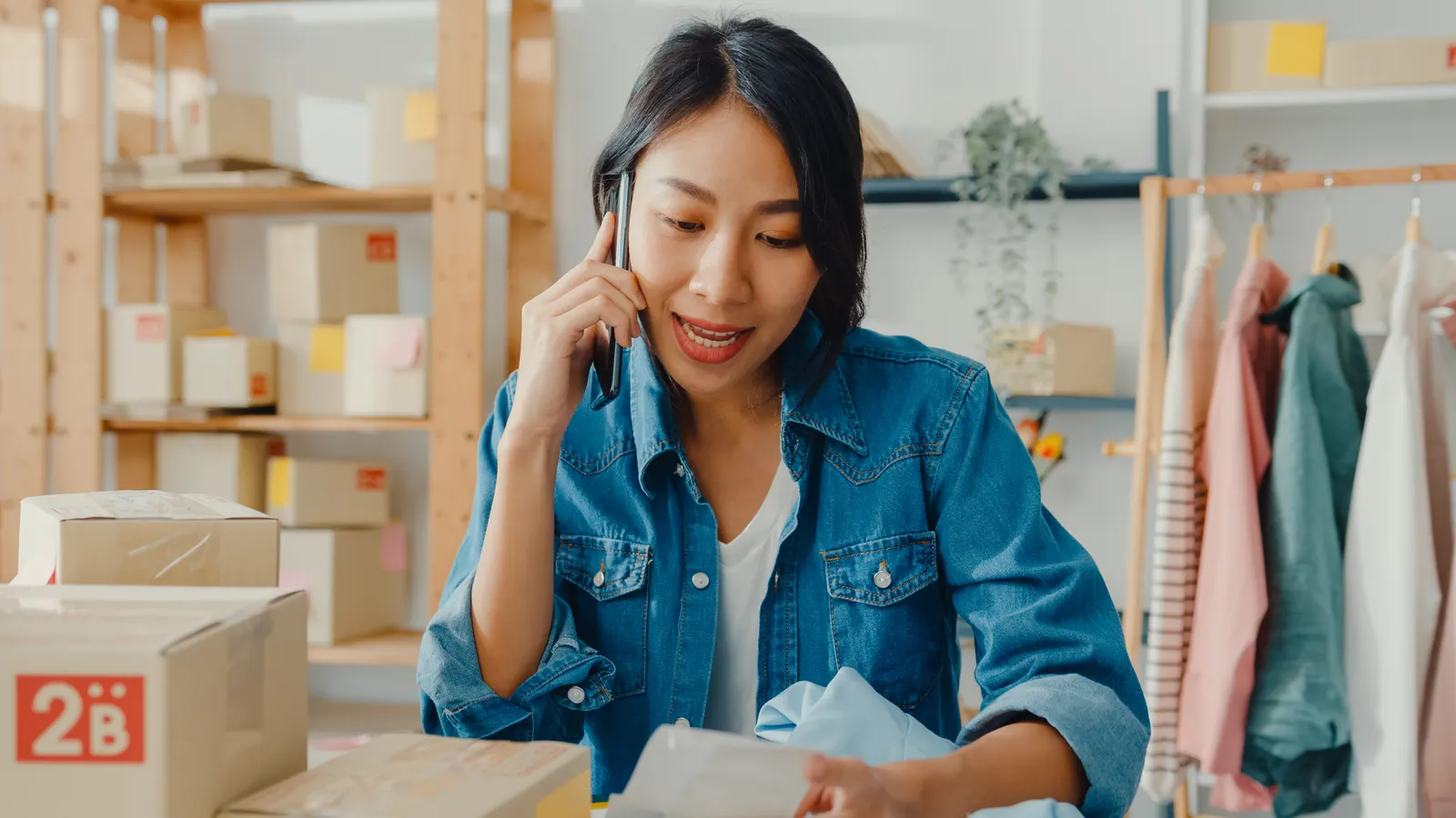 A distributor on the phone beside packed boxes, going through an order that has just come in.