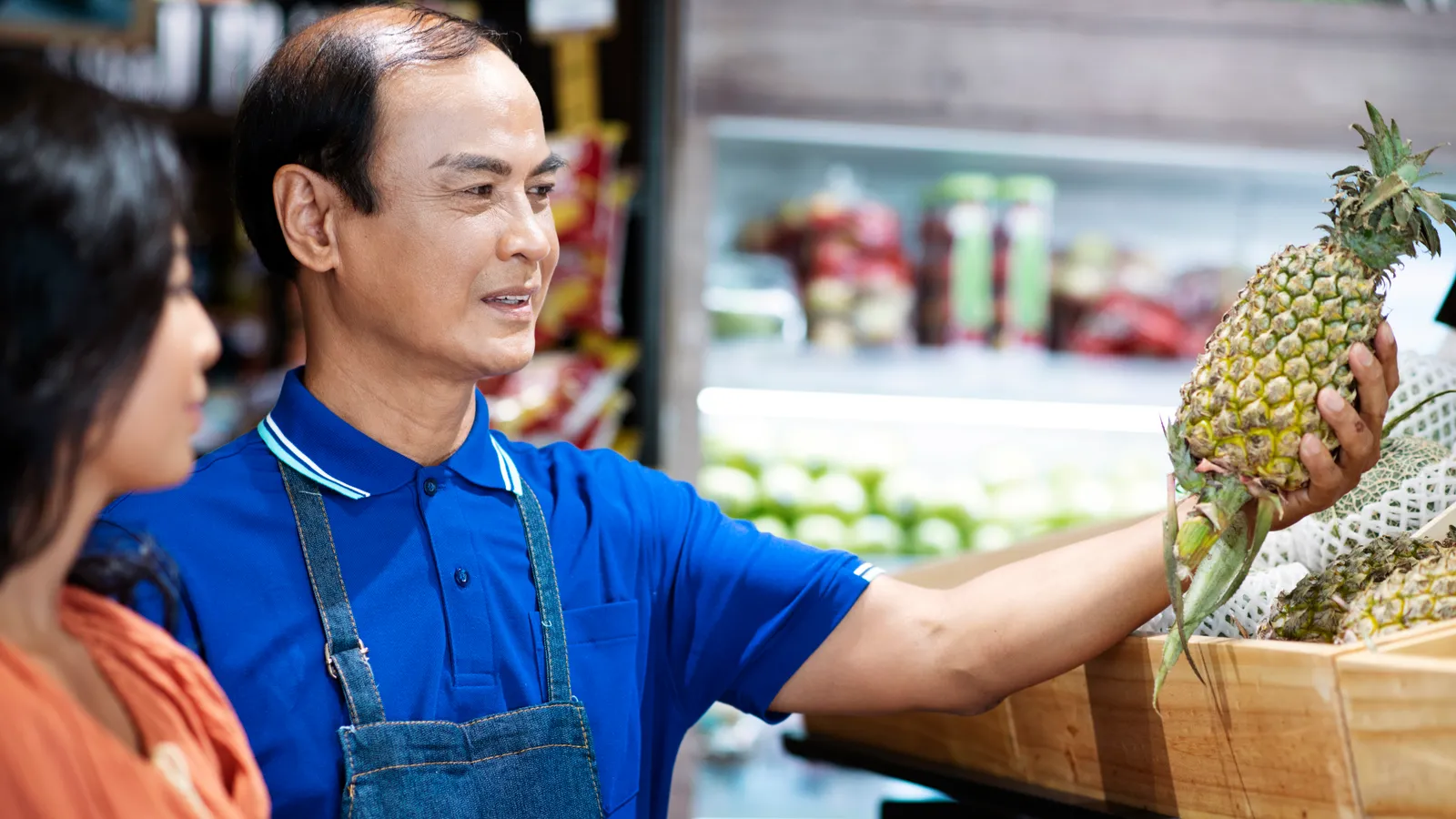A neighbourhood shopkeeper serving a customer at the counter of their store.